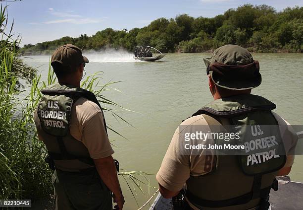 Border Patrol agents watch colleagues motor past while patrolling for illegal immigrants in the Rio Grande River crossing into the United States...