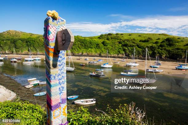 solva harbour, pembrokeshire, uk with a yarn bombed signpost. - pembrokeshire stock pictures, royalty-free photos & images
