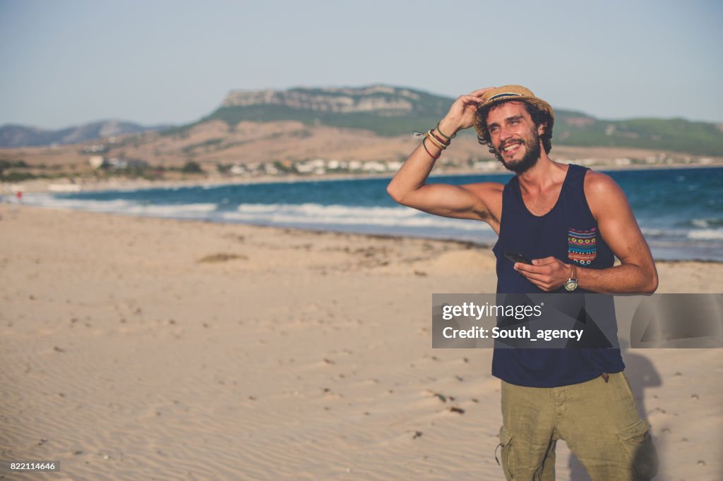 Young Hipster man op het strand met telefoon