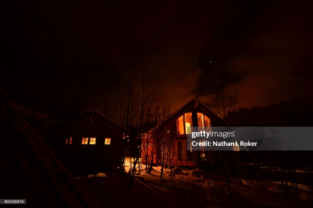 A nightime view of Norwegian cabin retreats, surrounded by snow.
