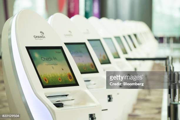 Automated touch screen passenger check-in machines stand during a media preview of the new Terminal 4 at Changi Airport in Singapore, on Tuesday,...