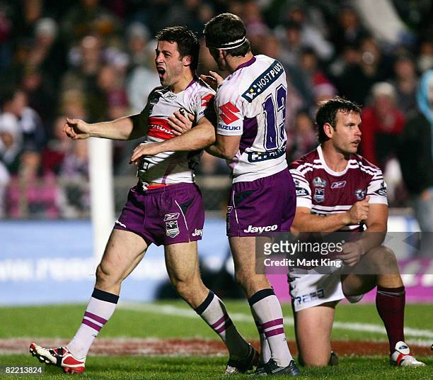 Cooper Cronk of the Storm celebrates with Dallas Johnson after scoring a try as Josh Perry of the Sea Eales looks on during the round 22 NRL match...