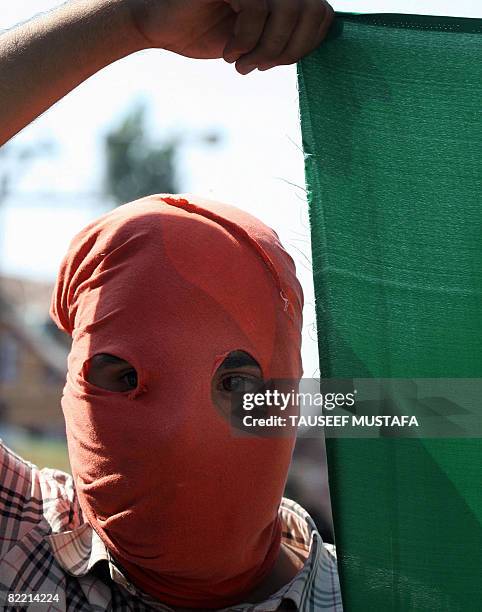 Masked Kashmiri Muslim holds a flag during a procession in Srinagar on August 8, 2008. Thousands of protestors were halted by security forces as they...