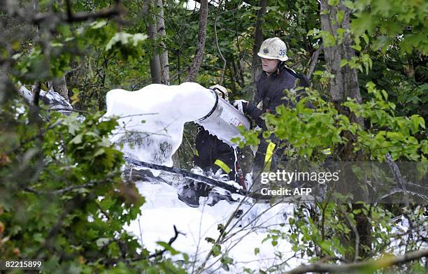 Firefighters extinguish a fire from the wreckage of the twin engine Diamond DA42 aircraft that crashed in a forest west of Stockholm after reporting...