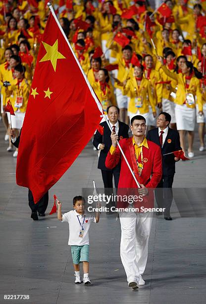 Yao Ming of the China Olympic men's basketball team carries his country's flag to lead out the delegation accompanied by Lin Hao, a 9-year old...