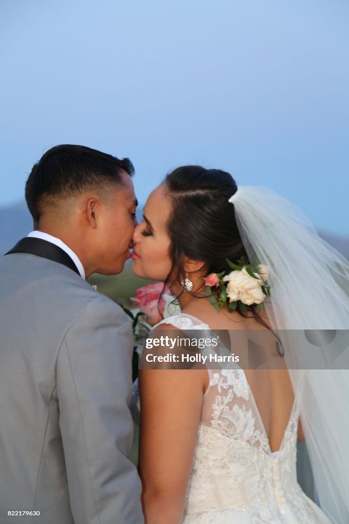 Bride and groom kissing at desert wedding at dusk