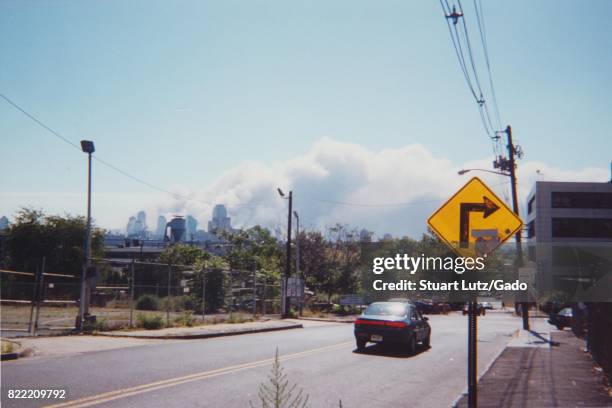 During the terrorist attacks of September 11 a car approaches an intersection as the sky is almost fully obscured by smoke rising from the buildings...