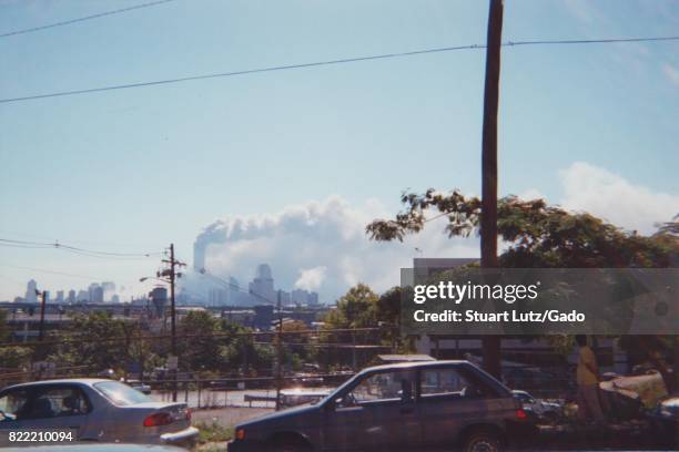 During the terrorist attacks of September 11 a man stands near a fence and parked cars in Jersey City, New Jersey while the South Tower of the World...