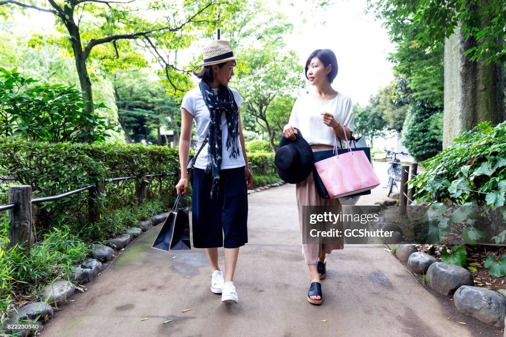 Women walking in a park with several bags in hand