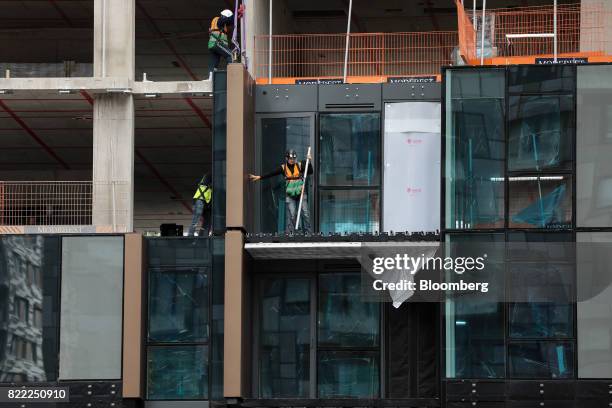 Construction workers fix windows and cladding onto the Harbour Central construction site, built by Galliard Homes Ltd., near the Canary Wharf...