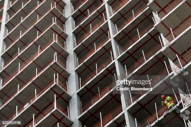 Worker looks out from the construction site of the Sailmakers building, being constructed by Greystar Europe Holdings Ltd., near the Canary Wharf...