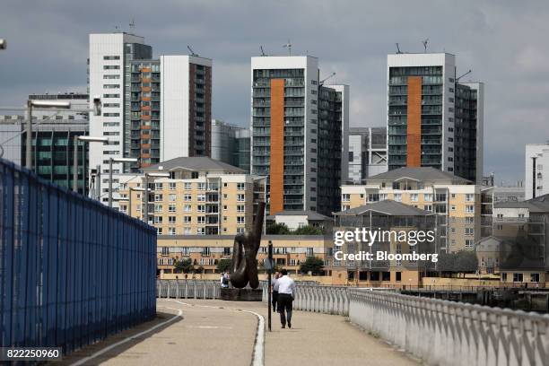 Pedestrian walks in view of residential flats in London, U.K., on Tuesday, July 25, 2017. U.K. House prices are "virtually at a standstill" as...