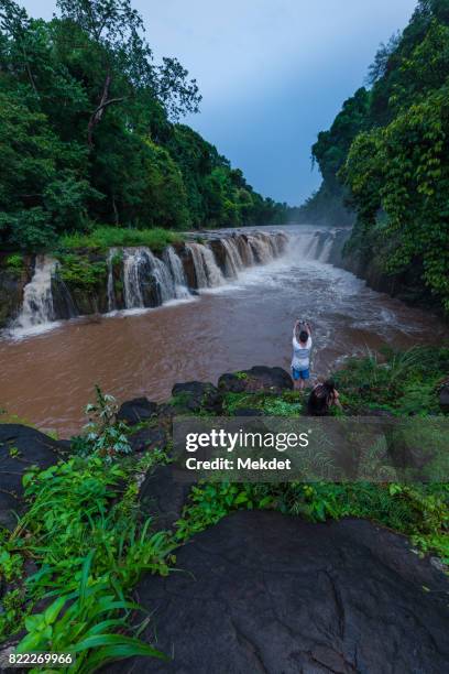 a tourist taking photo of pha suam waterfall, bolaven plateau, champasak province, laos - meseta de bolaven fotografías e imágenes de stock