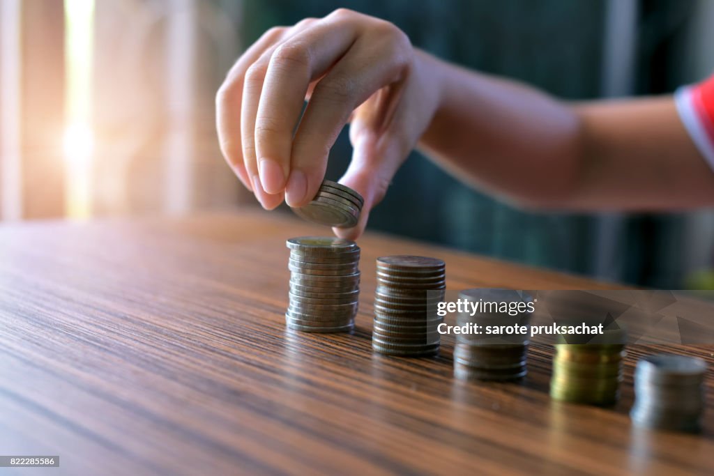 Boy Hand Put Coins To Stack Of Coins .savings, finances, economy and home concept