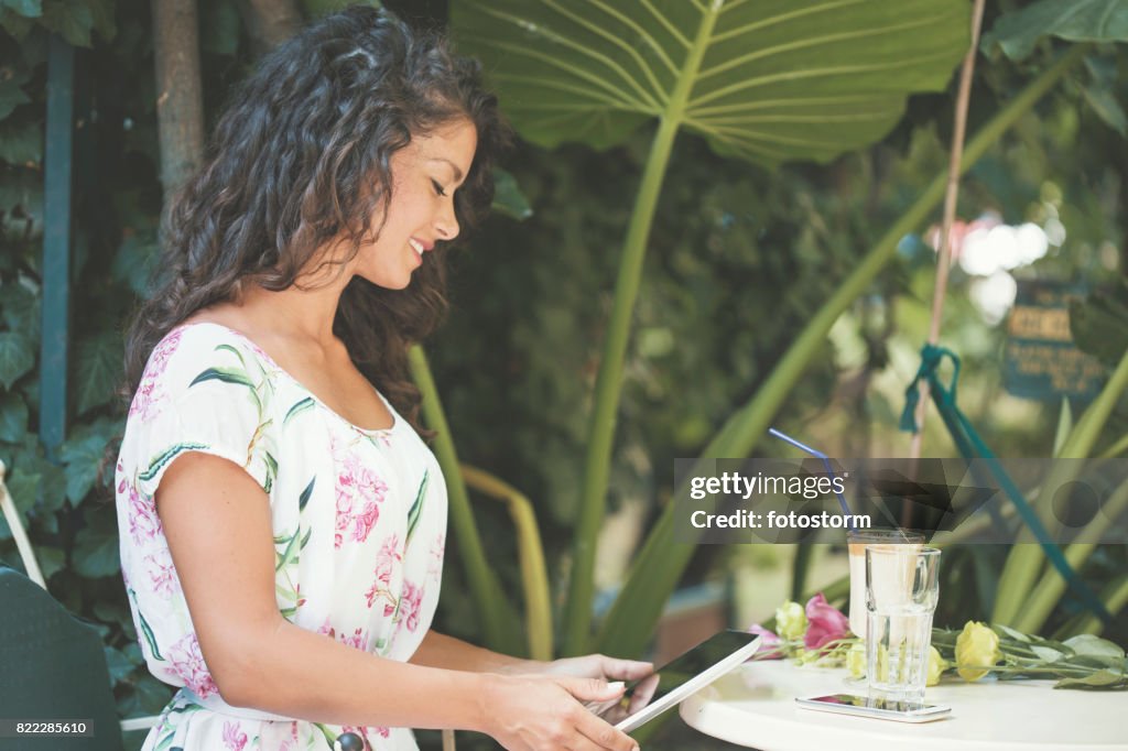 Jovem mulher relaxante no café jardim