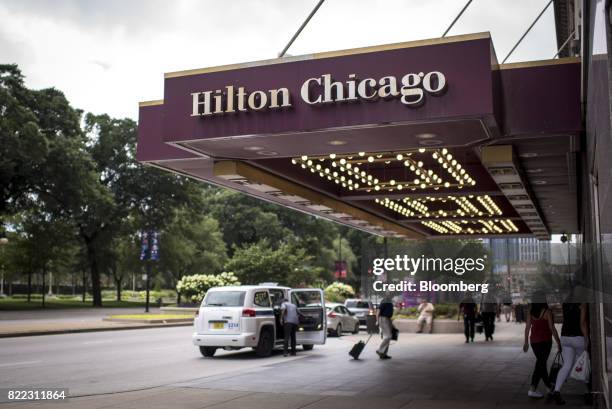 Guests walk towards the entrance of Hilton Chicago hotel in downtown Chicago, Illinois, U.S., on Monday, July 24, 2017. Hilton Worldwide Holdings...