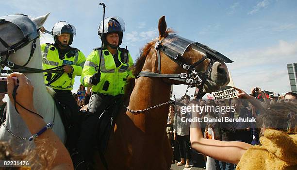 Mounted police officer raises her riding crop as an activist grabs hold of the reins of her horse during a march by protestors towards Kingsnorth...