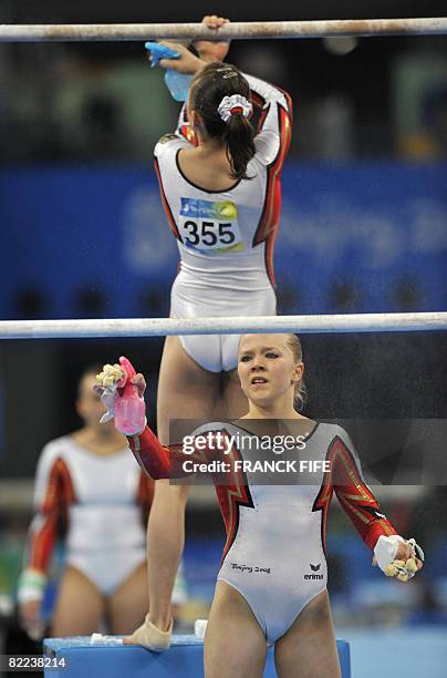 Germany's Anja Brinker and her teammate Joeline Mobius get ready to compete on the uneven bars during the women's qualification of the artistic...