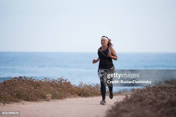 young plump woman running outdoors along the seacoast. - marathon start stock pictures, royalty-free photos & images