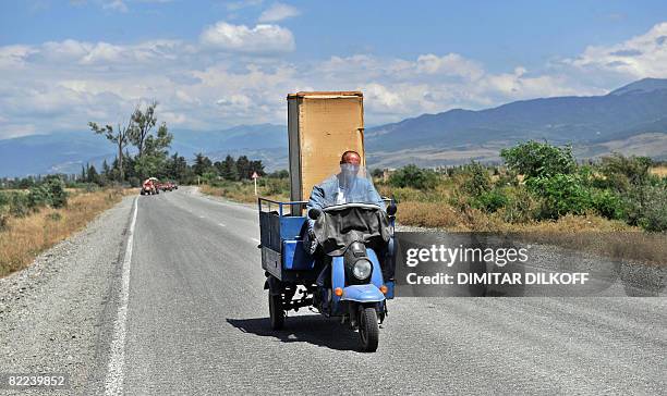 Georgian man rides a three-wheeled vehicle as he flees in South Ossetia near the village of Troiavi on August 10, 2008. Russian troops are heading...