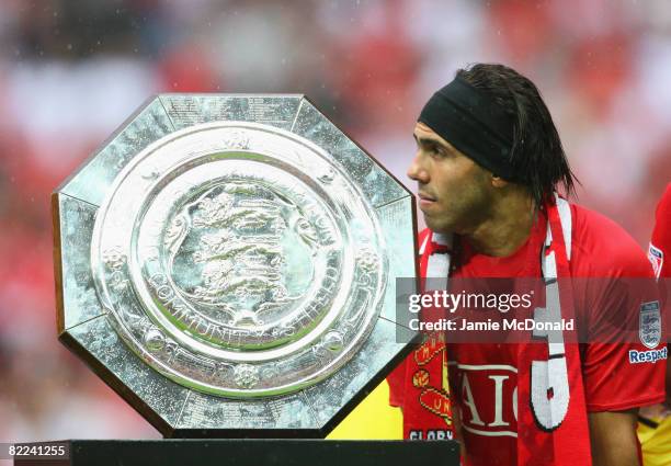 Carlos Tevez of Manchester United stands with the trophy as they are victorious on penalty kicks during the FA Community Shield match between...