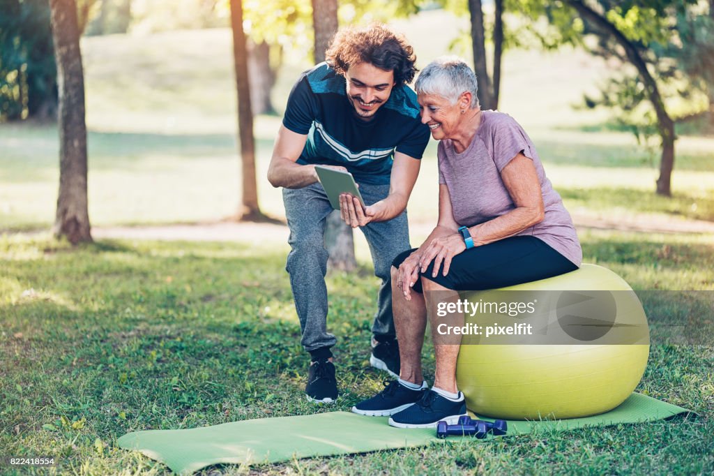 Fitness instructor and senior woman with digital tablet