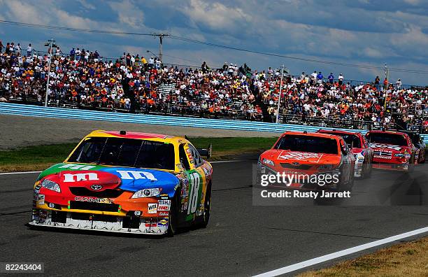 Kyle Busch, driver of the M&M's Toyota leads Tony Stewart, driver of the Home Depot Toyota, Marcos Ambrose, driver of the Little Debbie Ford, and...