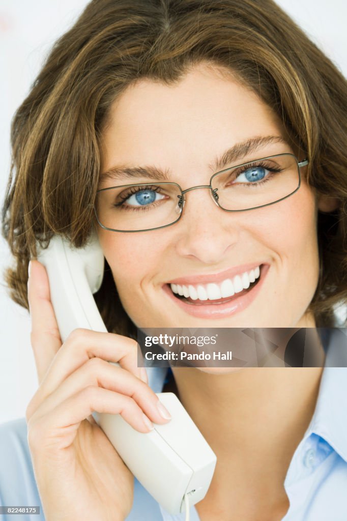 Woman using telephone, smiling