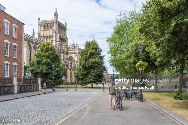 hombre empuja una bicicleta por una carretera cerca de la catedral de bristol - bristol fotografías e imágenes de stock