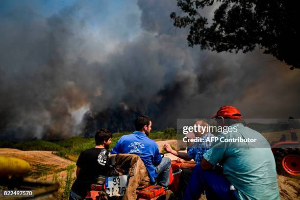 People chat as they watch the progression of a wildfire at Carvoeiro in Macao, central Portugal, on July 25, 2017. / AFP PHOTO / PATRICIA DE MELO...