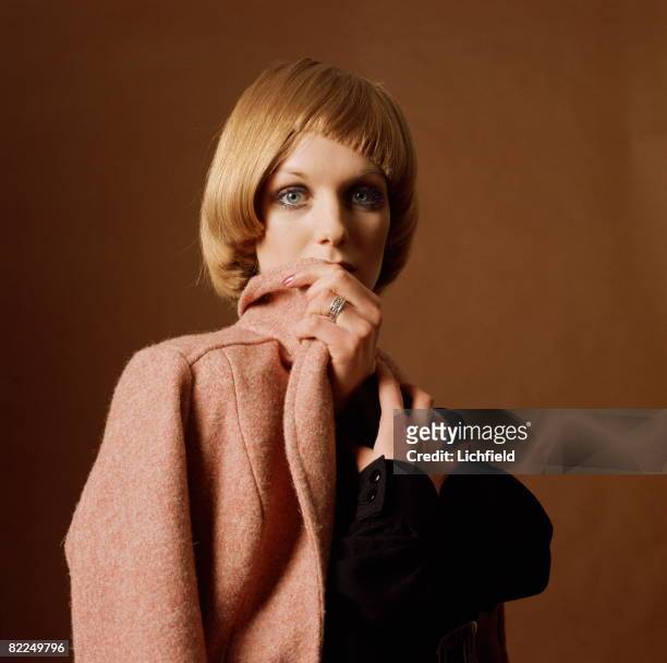 Model with a fashionable haircut holding a pink wool coat, photographed in the Studio on 3rd March 1969. .