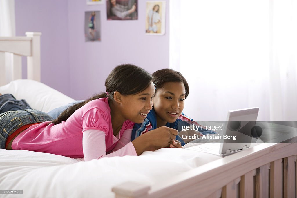 Two girls watching dvd player on bed
