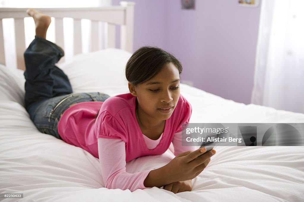 Girl looking at mobile phone on bed