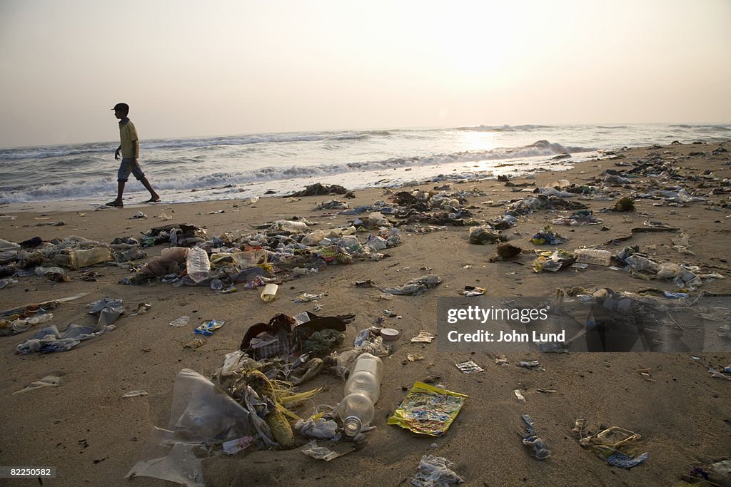 Man walking on a beach full of garbage
