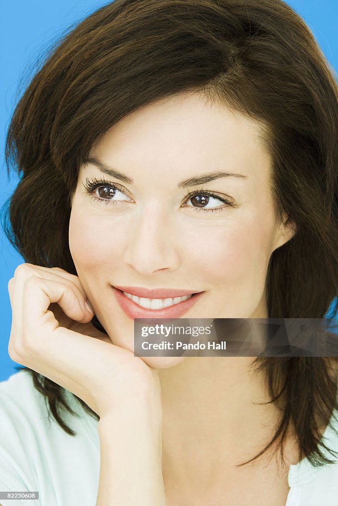 Woman smiling resting head on hand, portrait