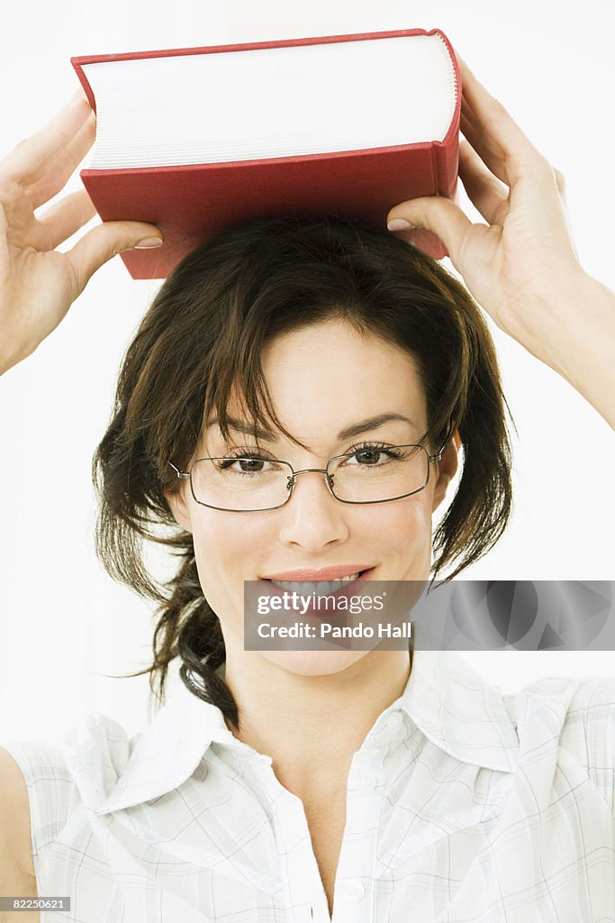 Woman carrying book on head, smiling, portrait