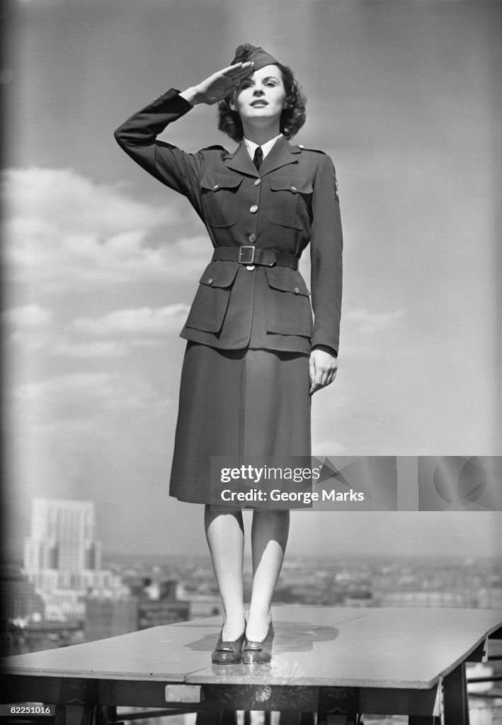 Female soldier standing on table and saluting