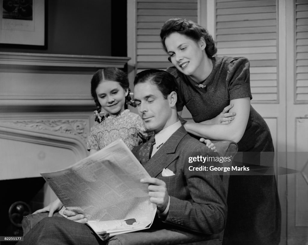 Parents with daughter (6-7 years) reading newspaper together