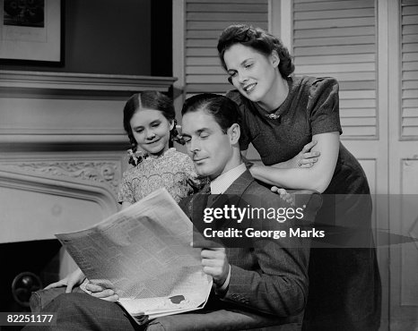 Parents with daughter (6-7 years) reading newspaper together