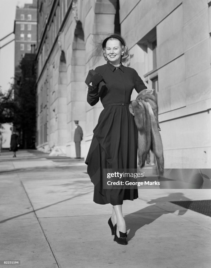 Portrait of mid adult woman walking along sidewalk