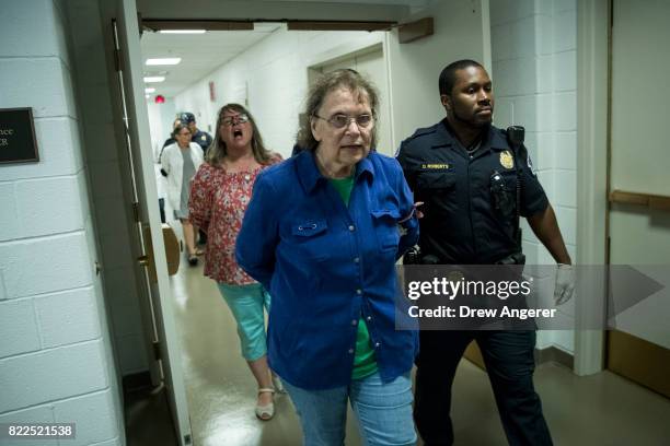 Protestors, who were removed from the Senate Chamber while protesting the GOP health care plan, are escorted out by U.S. Capitol Police officers on...