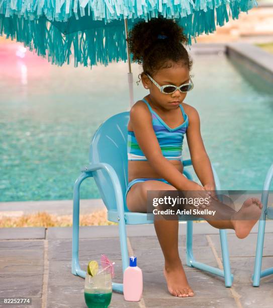 young girl sitting by pool putting on sun screen - putting lotion stock pictures, royalty-free photos & images