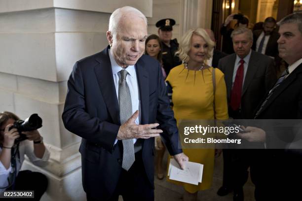 Senator John McCain, a Republican from Arizona, center, exits the U.S. Capitol with his wife Cindy McCain, center right, after voting on the Senate...