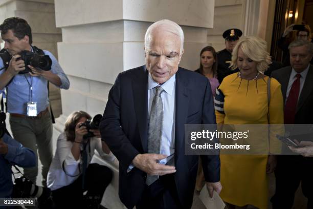 Senator John McCain, a Republican from Arizona, center, exits the U.S. Capitol with his wife Cindy McCain, center right, after voting on the Senate...