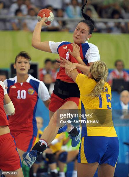 Irina Poltoratskaya Russia takes a shoot for a goal as Swedish player Johanna Ahlm trying to block her try to block her during their 2008 Olympics...