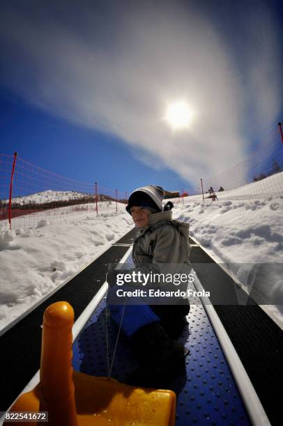 boy rides 'magic carpet' ski escalator - 空飛ぶ絨毯 ストックフォトと画像