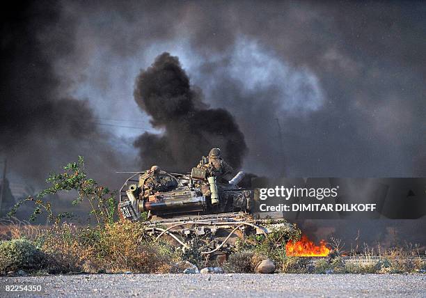 Georgian soldiers sit on a tank as a Russian rocket fire hits a convoy of departing Georgian troops just outside Gori on August 11, 2008. Russian...