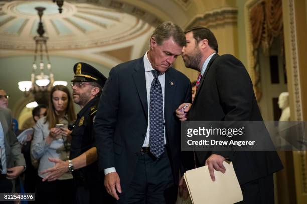 Sen. David Perdue speaks with an aide as he walks to the Senate floor for a procedural vote on the GOP heath care plan, on Capitol Hill, July 25,...
