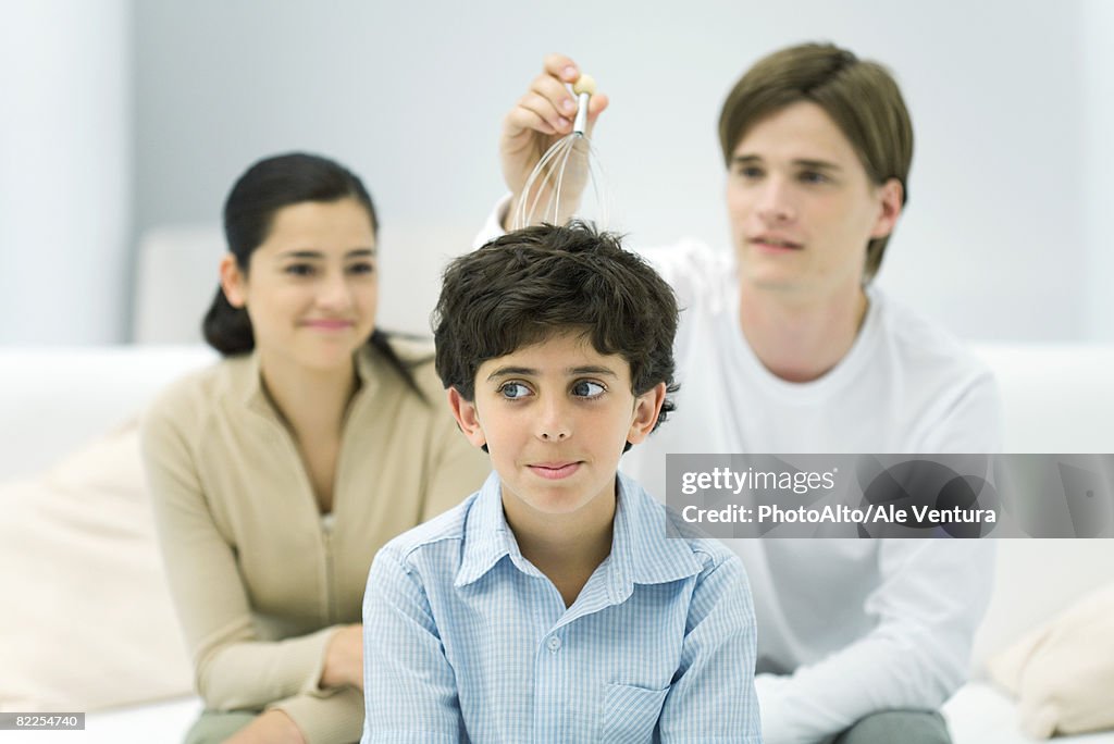 Young man and woman with boy, trying out head massager