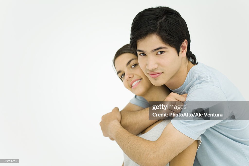 Young couple embracing, smiling at camera